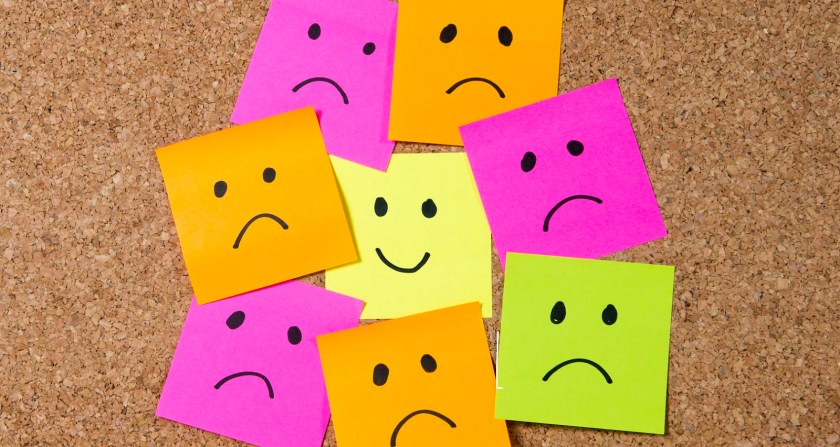 smiley post it note on corkboard happiness versus depression concept